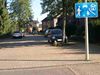 beginning of a living street with a paving stones surface and some trees and cars parking at the sides